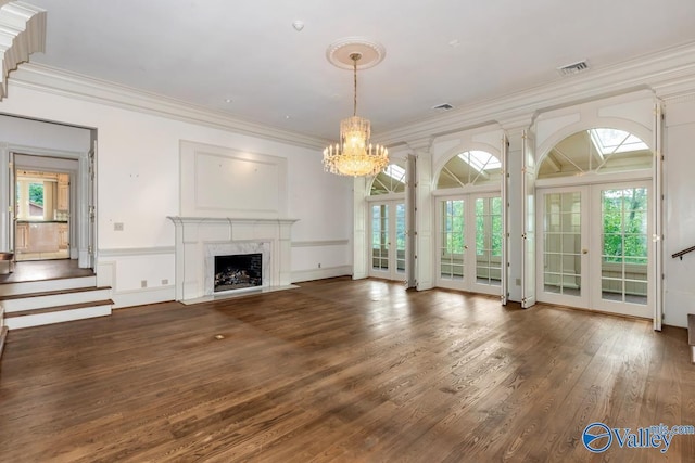 unfurnished living room with crown molding, a notable chandelier, visible vents, and french doors