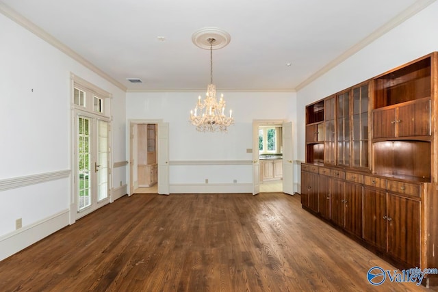 unfurnished dining area featuring dark wood-style flooring, visible vents, crown molding, and a chandelier