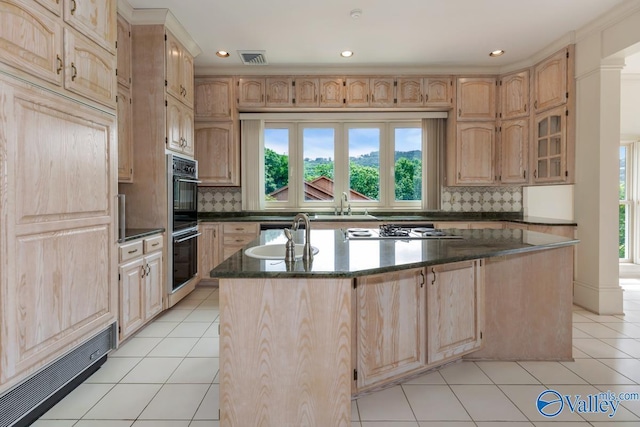 kitchen featuring light brown cabinetry, an island with sink, and a sink