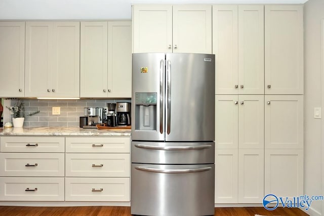 kitchen with tasteful backsplash, light stone countertops, stainless steel fridge with ice dispenser, white cabinetry, and wood-type flooring