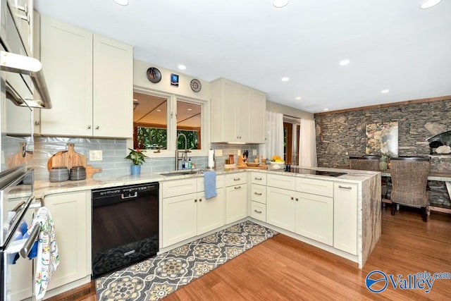 kitchen with black appliances, sink, kitchen peninsula, light hardwood / wood-style floors, and decorative backsplash