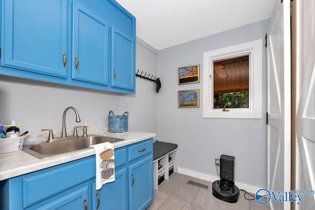 kitchen featuring light tile patterned floors, sink, and blue cabinetry