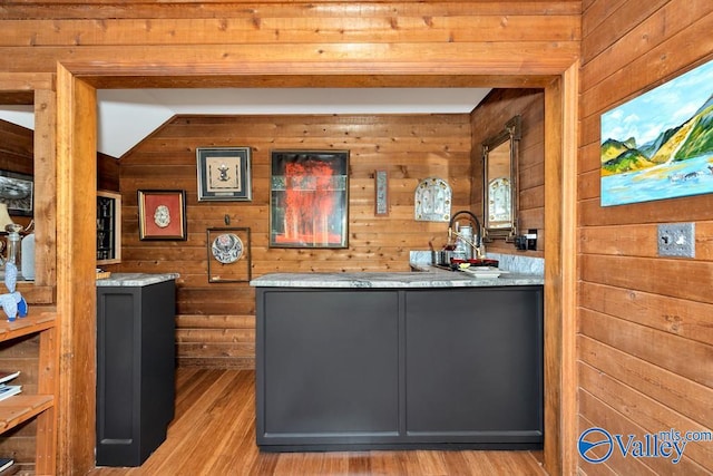 bar with wood walls, light hardwood / wood-style flooring, and gray cabinetry