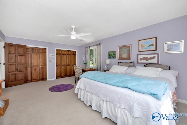 carpeted bedroom with two closets and ceiling fan