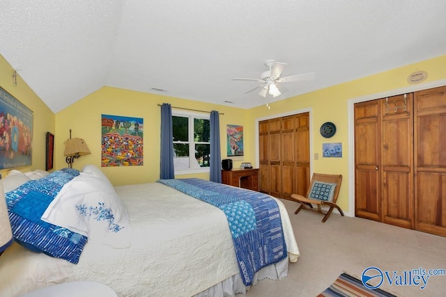 carpeted bedroom with two closets, ceiling fan, and lofted ceiling