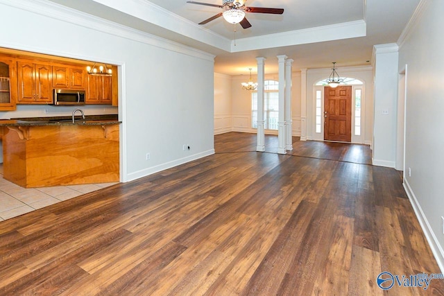 300 Honor Way, Madison, AL 35758 - unfurnished living room featuring a chandelier, ceiling fan, wood finished floors, ornamental molding, and a tray ceiling