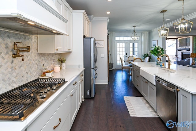 kitchen featuring pendant lighting, sink, premium range hood, white cabinetry, and stainless steel appliances