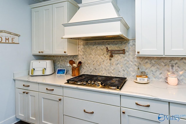 kitchen with tasteful backsplash, stainless steel gas cooktop, custom exhaust hood, and white cabinets