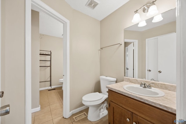 bathroom with tile patterned floors, toilet, vanity, and a textured ceiling