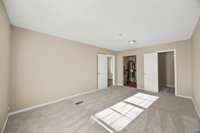 unfurnished bedroom featuring a closet, carpet flooring, and electric water heater