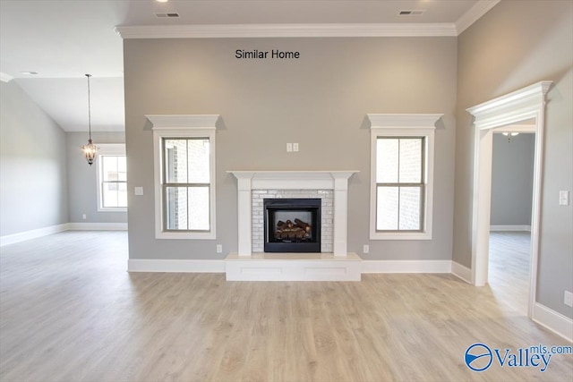 unfurnished living room with light wood-type flooring, a chandelier, and crown molding