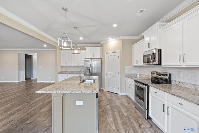 kitchen featuring stainless steel appliances, light hardwood / wood-style flooring, white cabinetry, hanging light fixtures, and an island with sink