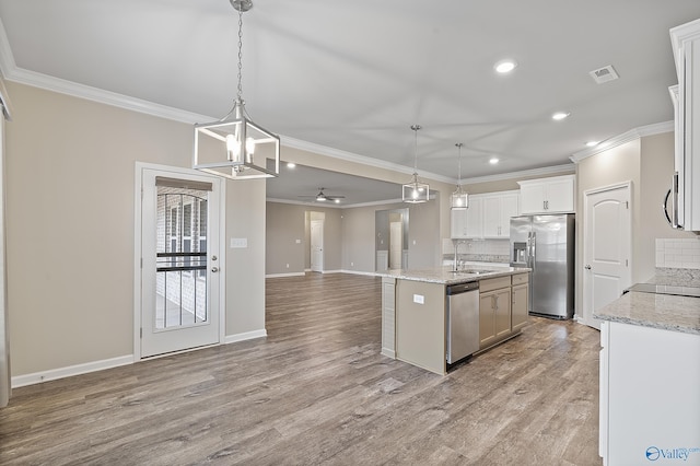 kitchen with hanging light fixtures, appliances with stainless steel finishes, ceiling fan with notable chandelier, and a kitchen island with sink