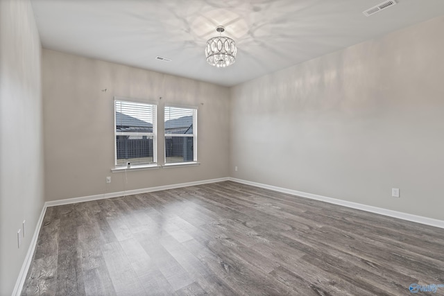 empty room featuring dark hardwood / wood-style floors and a notable chandelier