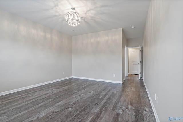 unfurnished room with a chandelier and dark hardwood / wood-style floors