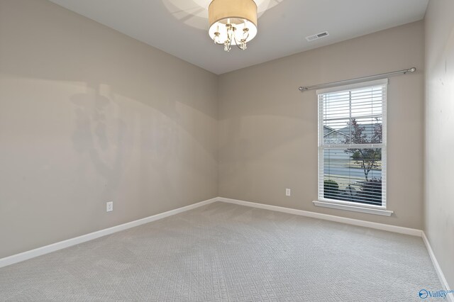 carpeted spare room with a notable chandelier