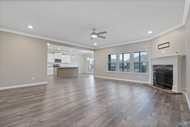 unfurnished living room featuring crown molding, ceiling fan, a stone fireplace, and dark wood-type flooring