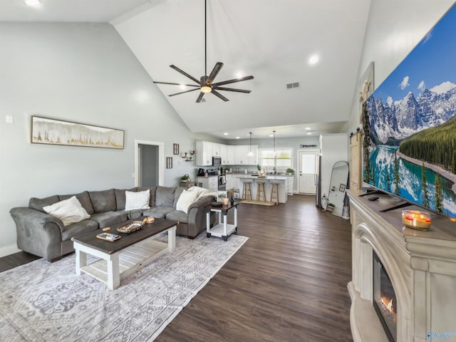 living room with ceiling fan, dark hardwood / wood-style flooring, and high vaulted ceiling