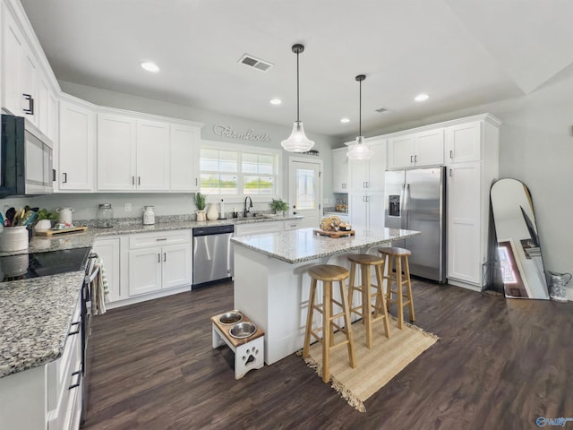 kitchen featuring a center island, white cabinets, sink, dark hardwood / wood-style flooring, and appliances with stainless steel finishes