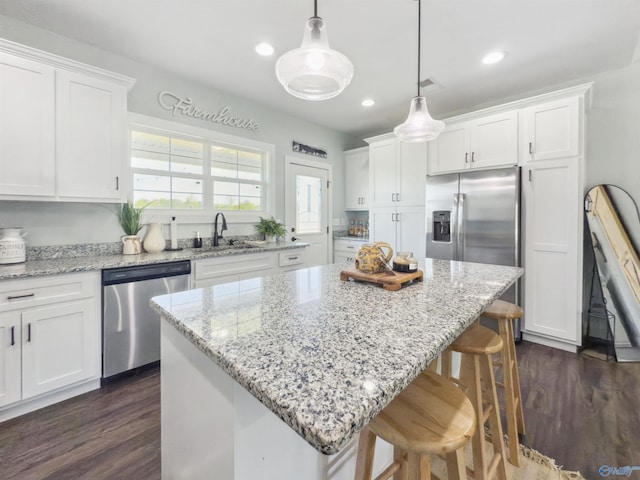 kitchen with appliances with stainless steel finishes, decorative light fixtures, a center island, and white cabinets