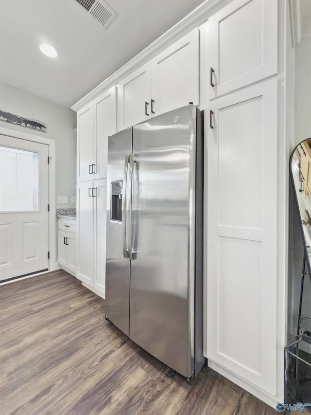 kitchen featuring white cabinets, light stone countertops, stainless steel fridge, and dark wood-type flooring