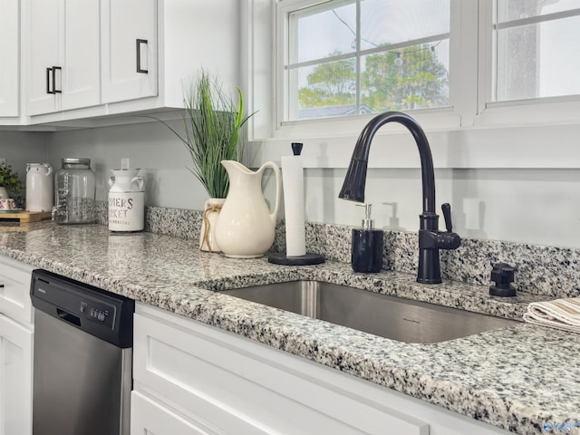 interior space featuring white cabinets, sink, stainless steel dishwasher, and light stone counters