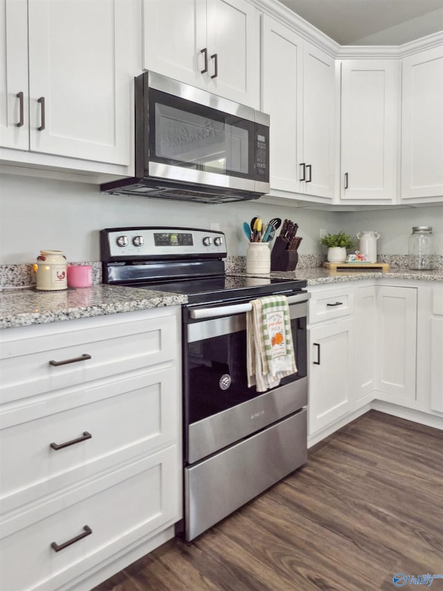 kitchen with light stone countertops, appliances with stainless steel finishes, dark wood-type flooring, and white cabinetry