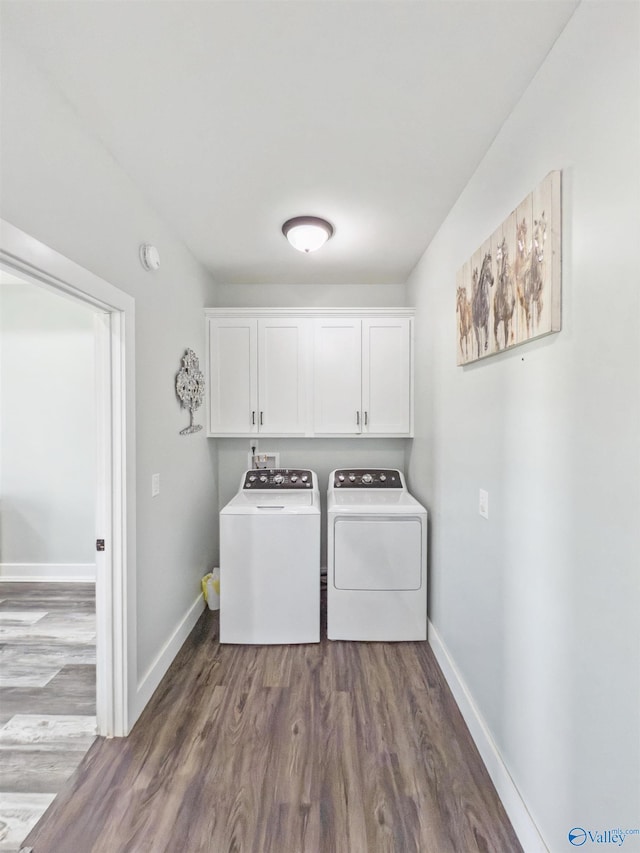 washroom with washing machine and clothes dryer, dark hardwood / wood-style floors, and cabinets