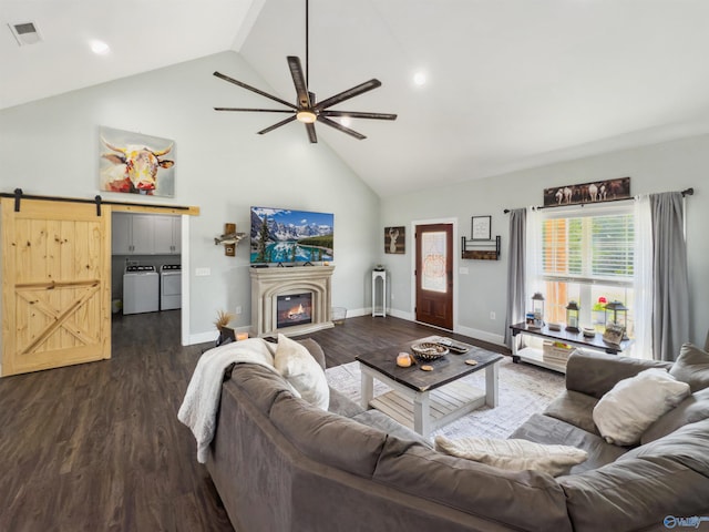 living room with high vaulted ceiling, independent washer and dryer, a barn door, and dark hardwood / wood-style floors