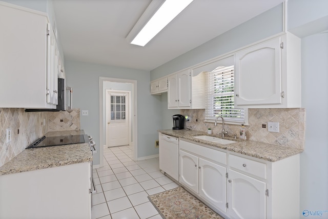 kitchen featuring white dishwasher, a sink, light tile patterned floors, white cabinets, and backsplash