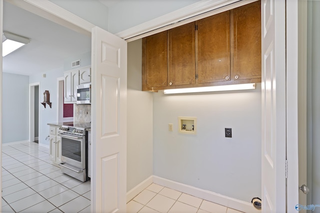 clothes washing area featuring hookup for an electric dryer, baseboards, hookup for a washing machine, laundry area, and light tile patterned floors