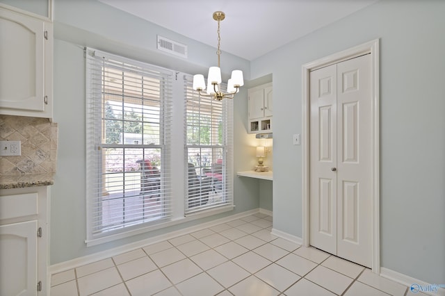 unfurnished dining area with a chandelier, visible vents, and baseboards