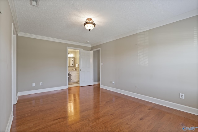 unfurnished room with wood finished floors, visible vents, crown molding, baseboards, and a textured ceiling