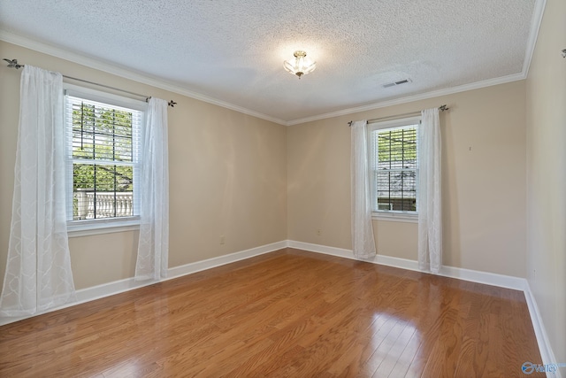 unfurnished room featuring a textured ceiling, baseboards, visible vents, wood finished floors, and crown molding