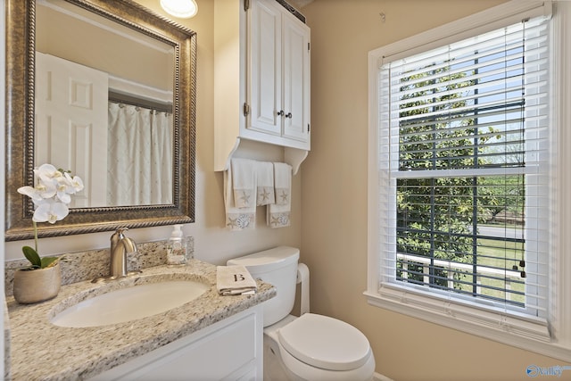 bathroom featuring plenty of natural light, toilet, vanity, and a shower with curtain