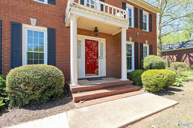 doorway to property with brick siding and a balcony