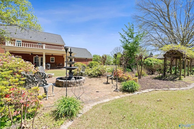 view of yard featuring a patio area, a balcony, and a ceiling fan