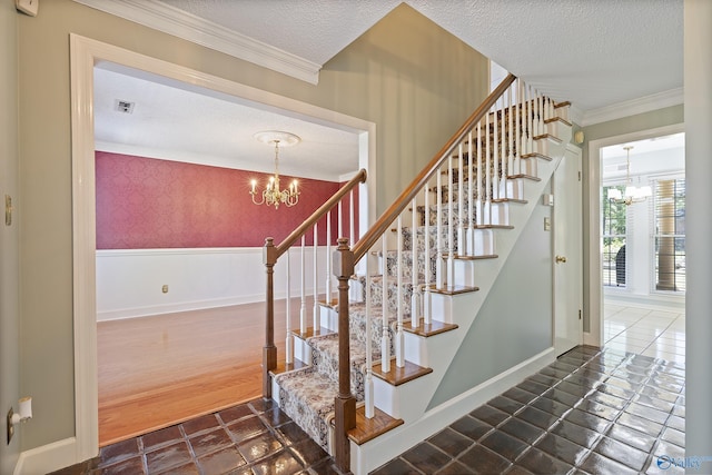 stairway with a textured ceiling, visible vents, crown molding, and an inviting chandelier