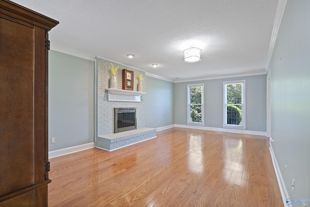 unfurnished living room featuring baseboards, ornamental molding, a textured ceiling, and light wood finished floors