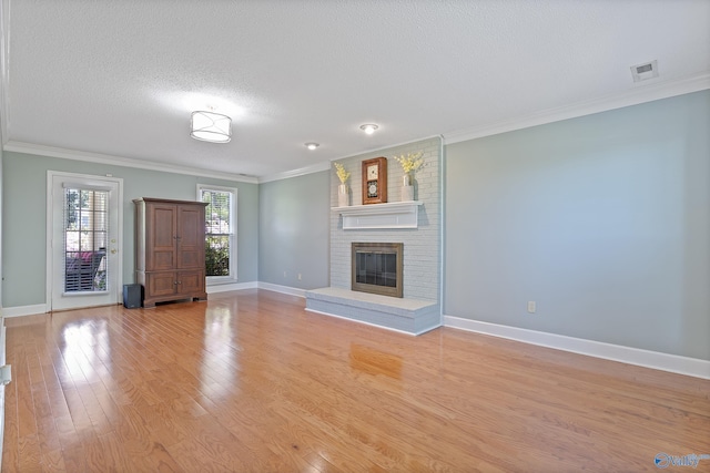 unfurnished living room featuring crown molding, light wood-style flooring, a fireplace, baseboards, and visible vents