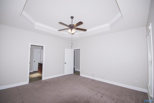 unfurnished bedroom featuring dark colored carpet, a tray ceiling, and ceiling fan