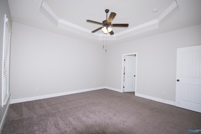 spare room featuring crown molding, a raised ceiling, dark colored carpet, and ceiling fan