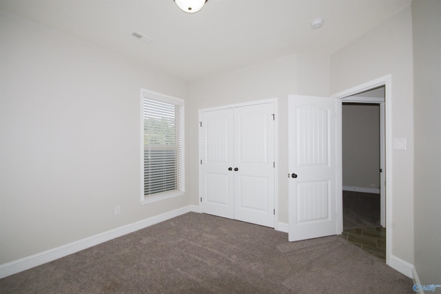 unfurnished bedroom with a closet and dark carpet