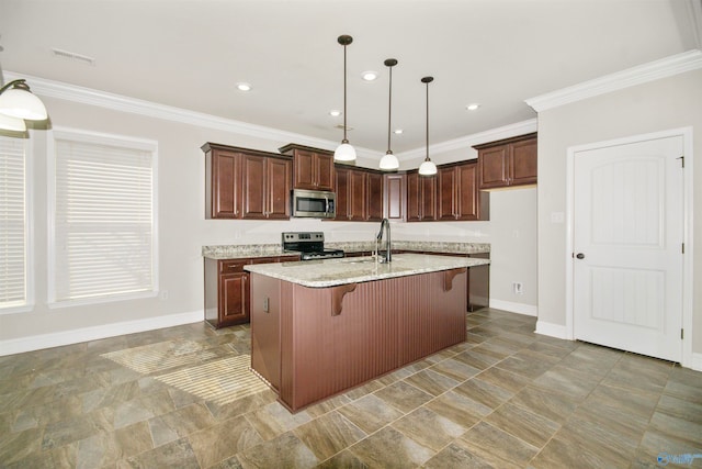 kitchen featuring appliances with stainless steel finishes, a kitchen bar, decorative light fixtures, light stone counters, and a kitchen island with sink