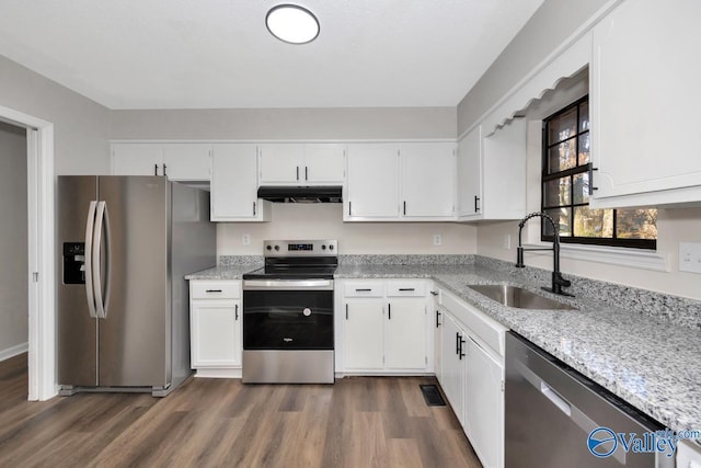 kitchen featuring appliances with stainless steel finishes, white cabinetry, sink, light stone counters, and dark wood-type flooring