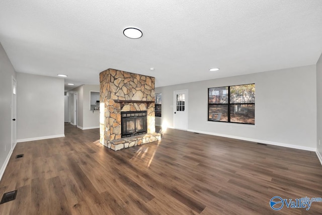 unfurnished living room featuring a stone fireplace, a textured ceiling, and dark hardwood / wood-style flooring