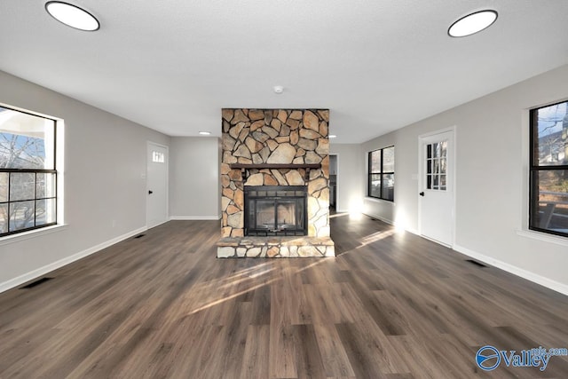 unfurnished living room featuring a fireplace, dark hardwood / wood-style floors, and a healthy amount of sunlight