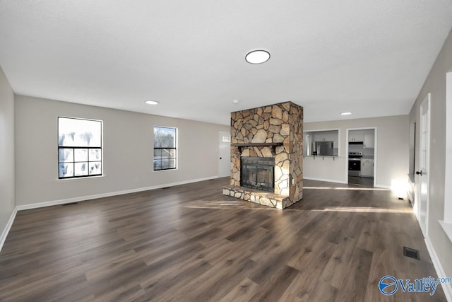 unfurnished living room featuring a stone fireplace, dark hardwood / wood-style floors, and a textured ceiling