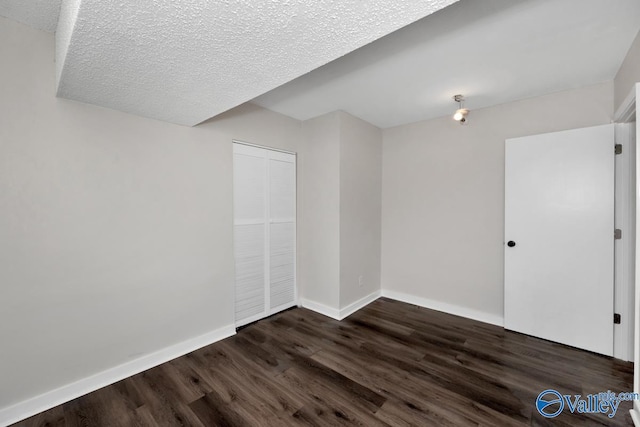 empty room featuring dark hardwood / wood-style floors and a textured ceiling