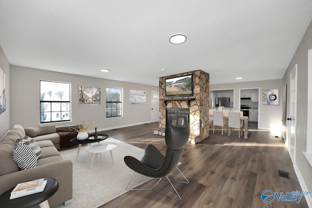 living room with dark hardwood / wood-style flooring, a textured ceiling, and a fireplace